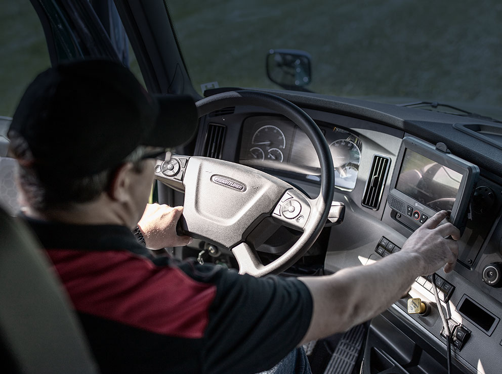 A McConnell Transport truck driver in a truck, using a touch screen